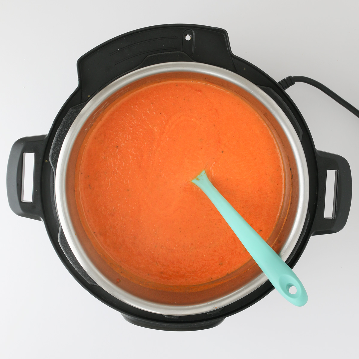 tomato soup in instant pot with teal spatula.