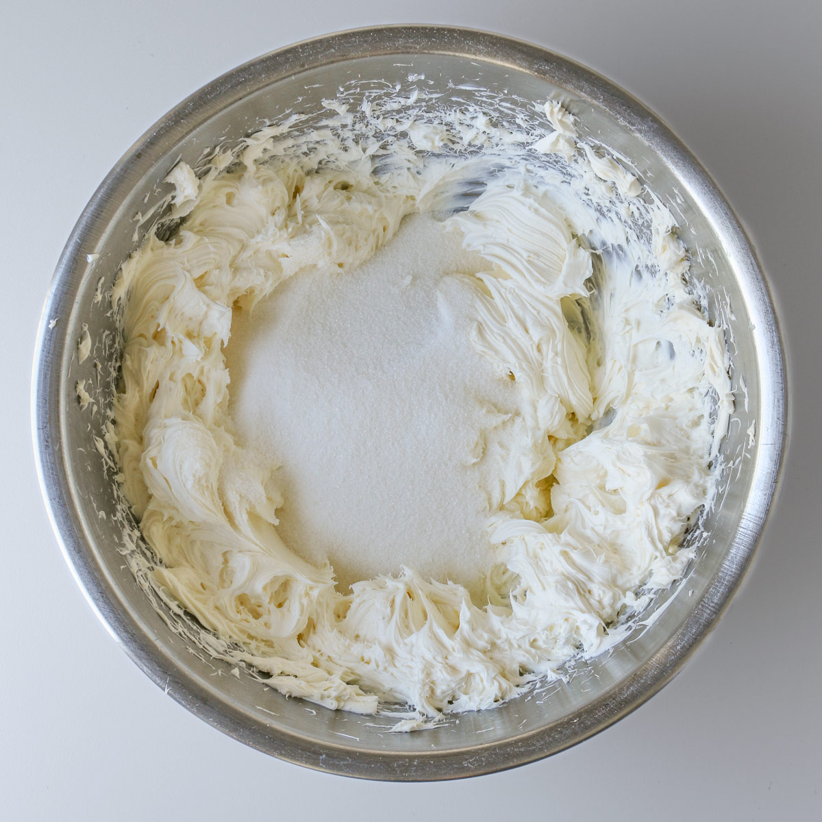 whipped cream cheese and sugar in metal mixing bowl.