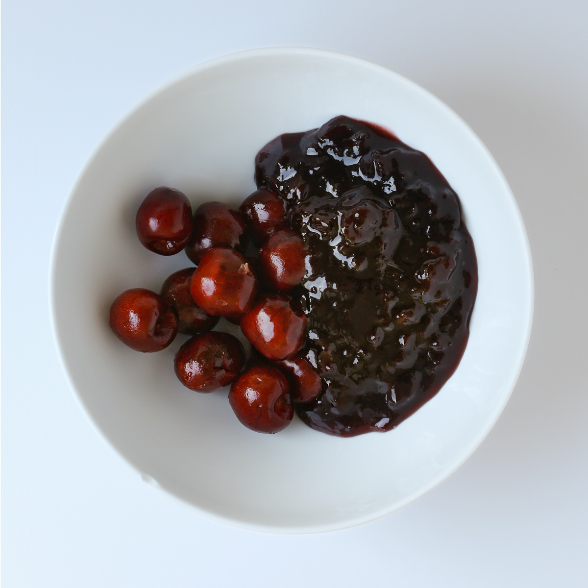 cherries and jam in white mixing bowl.