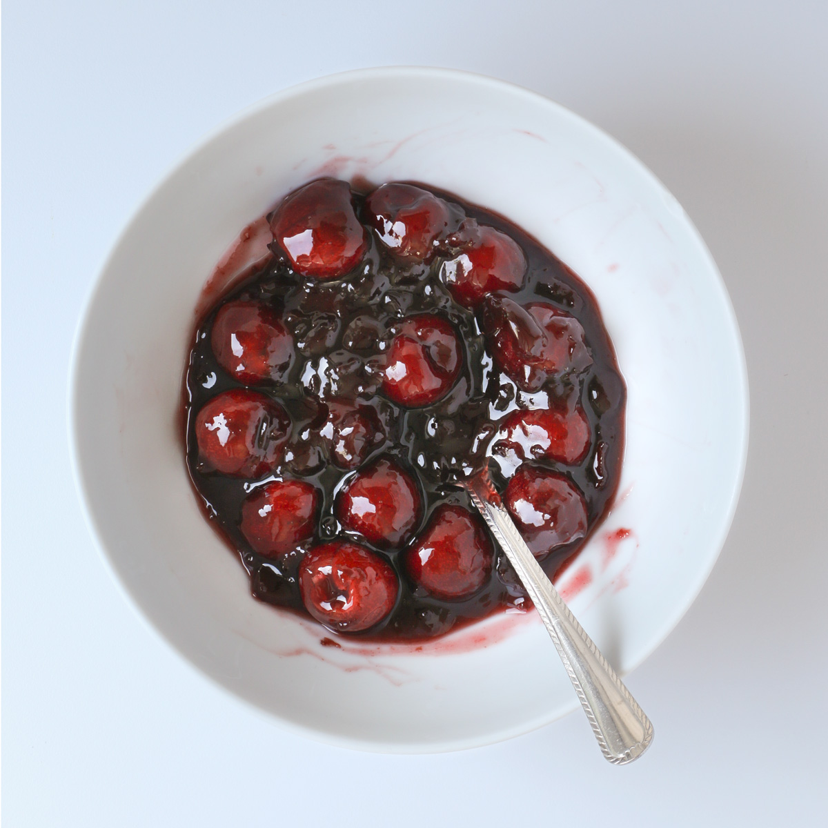 cherry topping combined in a bowl with silver spoon.