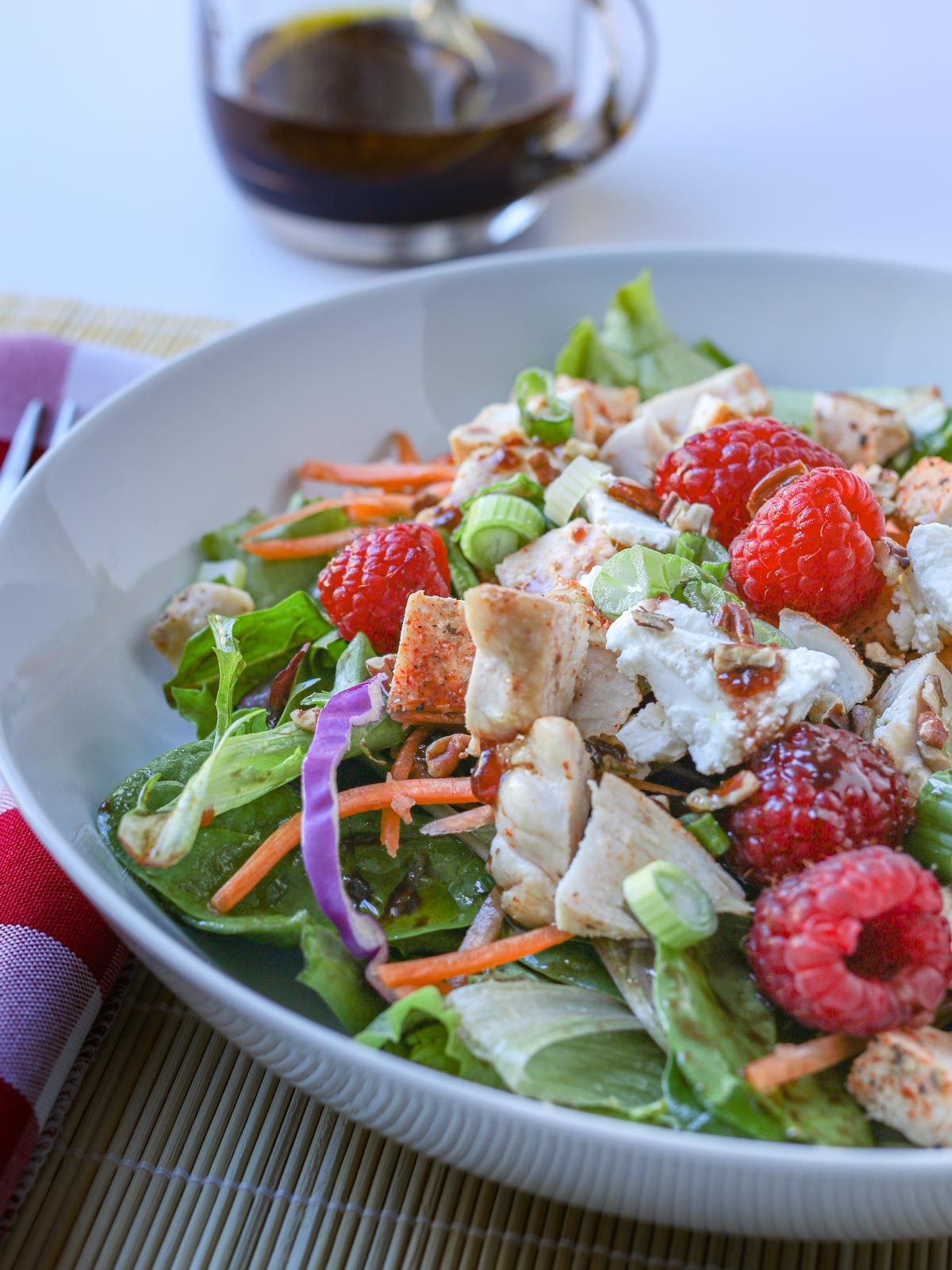 close up of salad with goat cheese, chicken, and raspberries. 