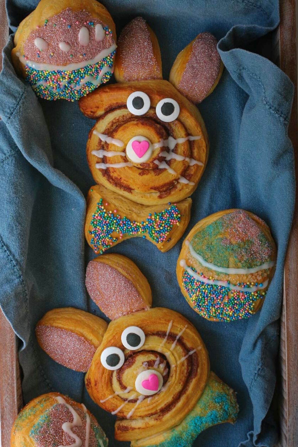 cinnamon roll easter bunnies and Easter egg biscuits in blue lined basket.