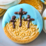 closeup of an easter oreo with crosses piped over a blue sky.