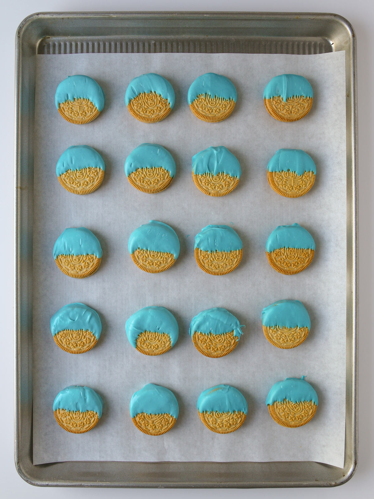 array of cookies dipped in blue candy melt on a lined tray.