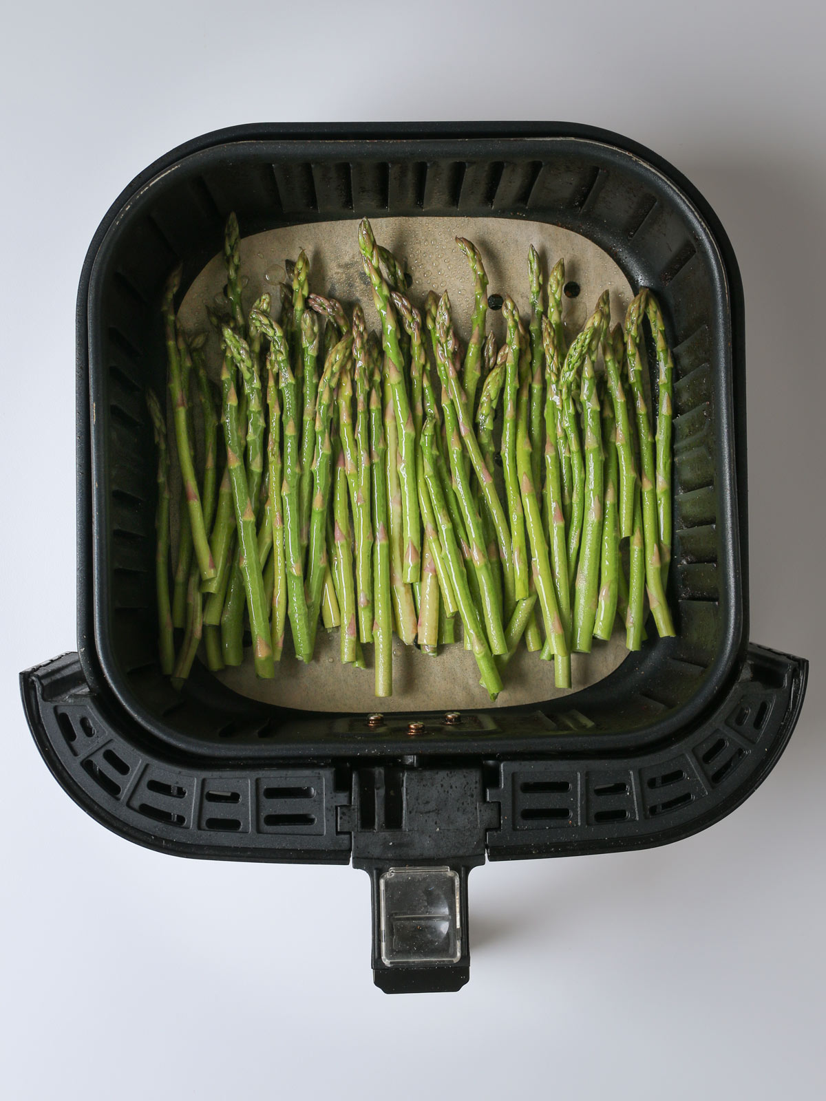 asparagus spears in air fryer basket.