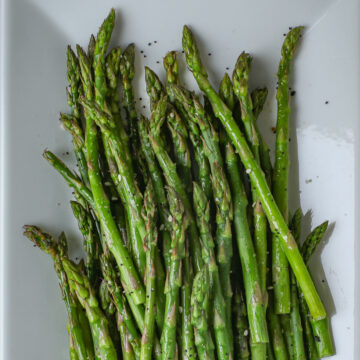 close up of air fryer asparagus on white platter.