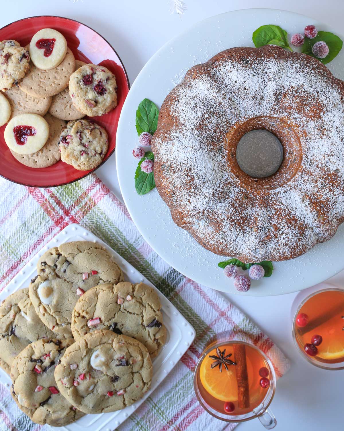 array of sweet treats on table: cake, cookies, and tea.