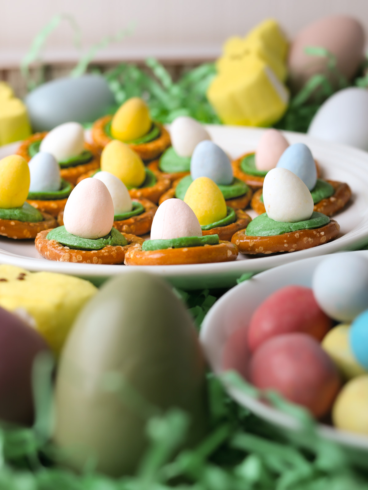 plate of Easter egg pretzels near other easter candy and eggs.