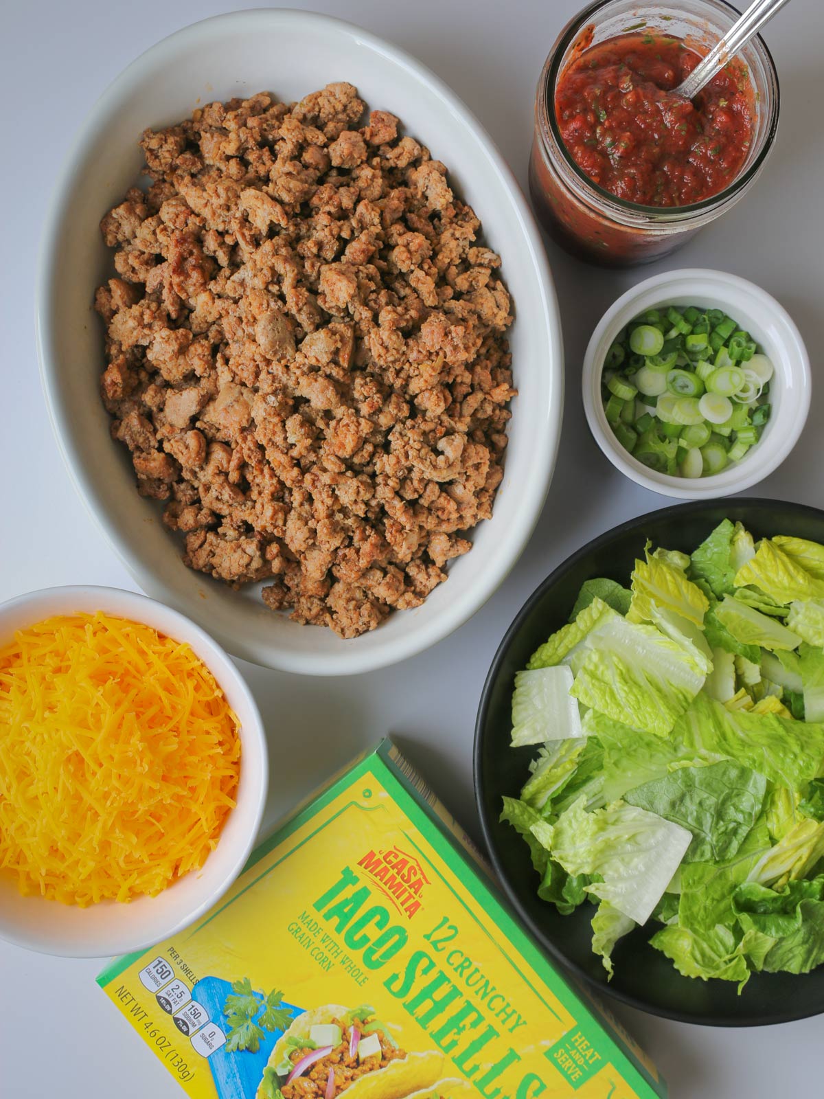 taco meat on table with box of taco shells and other taco fillings.