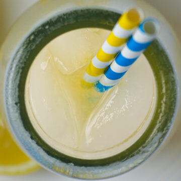 overhead shot of milk jar full of ginger lemonade with ice and straws.