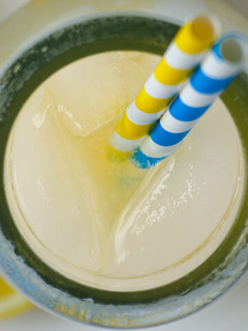 overhead shot of milk jar full of ginger lemonade with ice and straws.