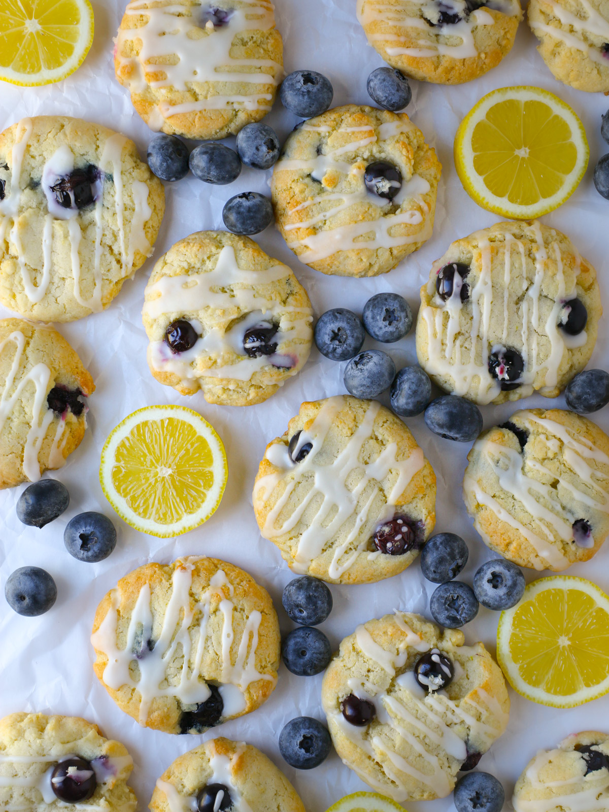 array of lemon blueberry cookies interspersed with lemon slices and fresh blueberries.