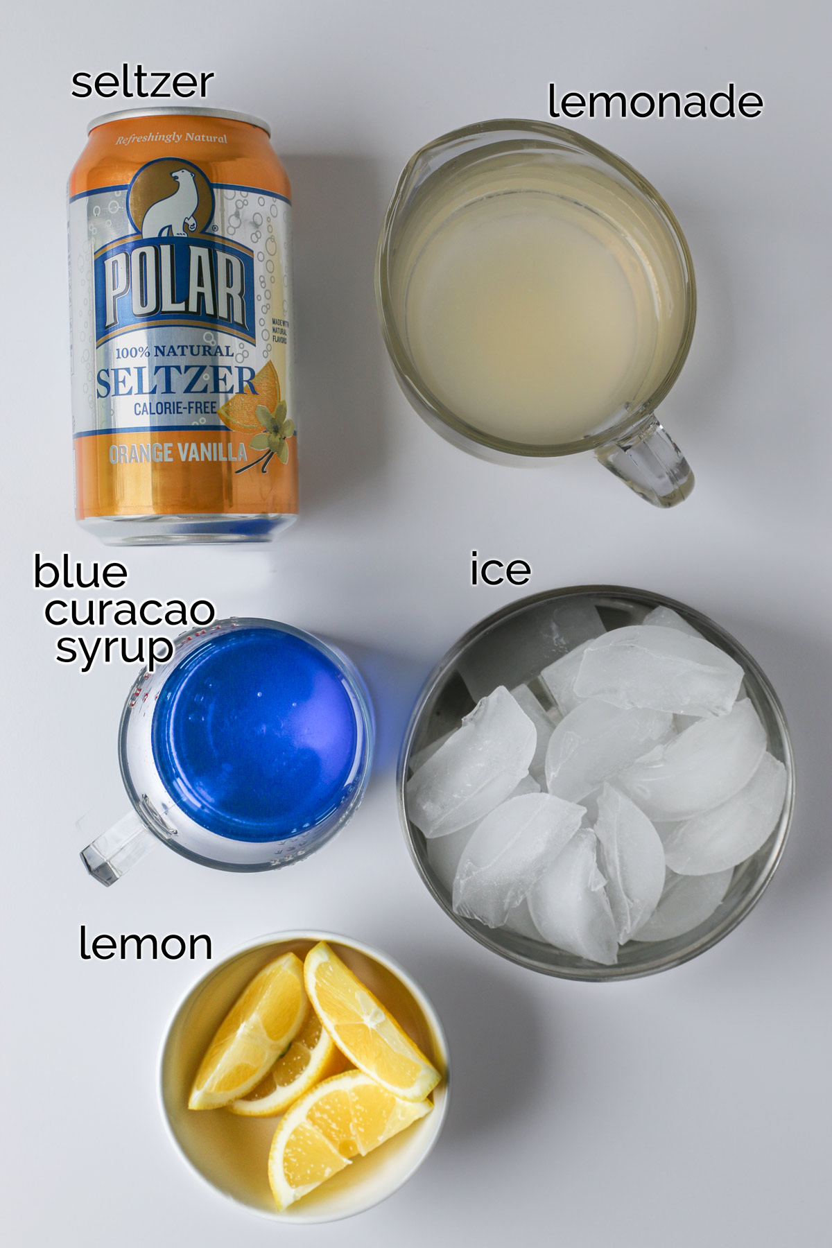 ingredients for blue lagoon mocktail laid out on a white counter.