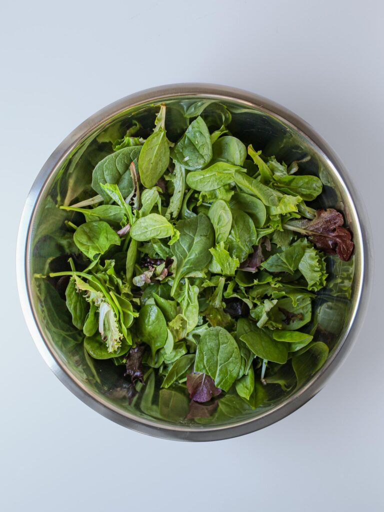 salad greens in large bowl.
