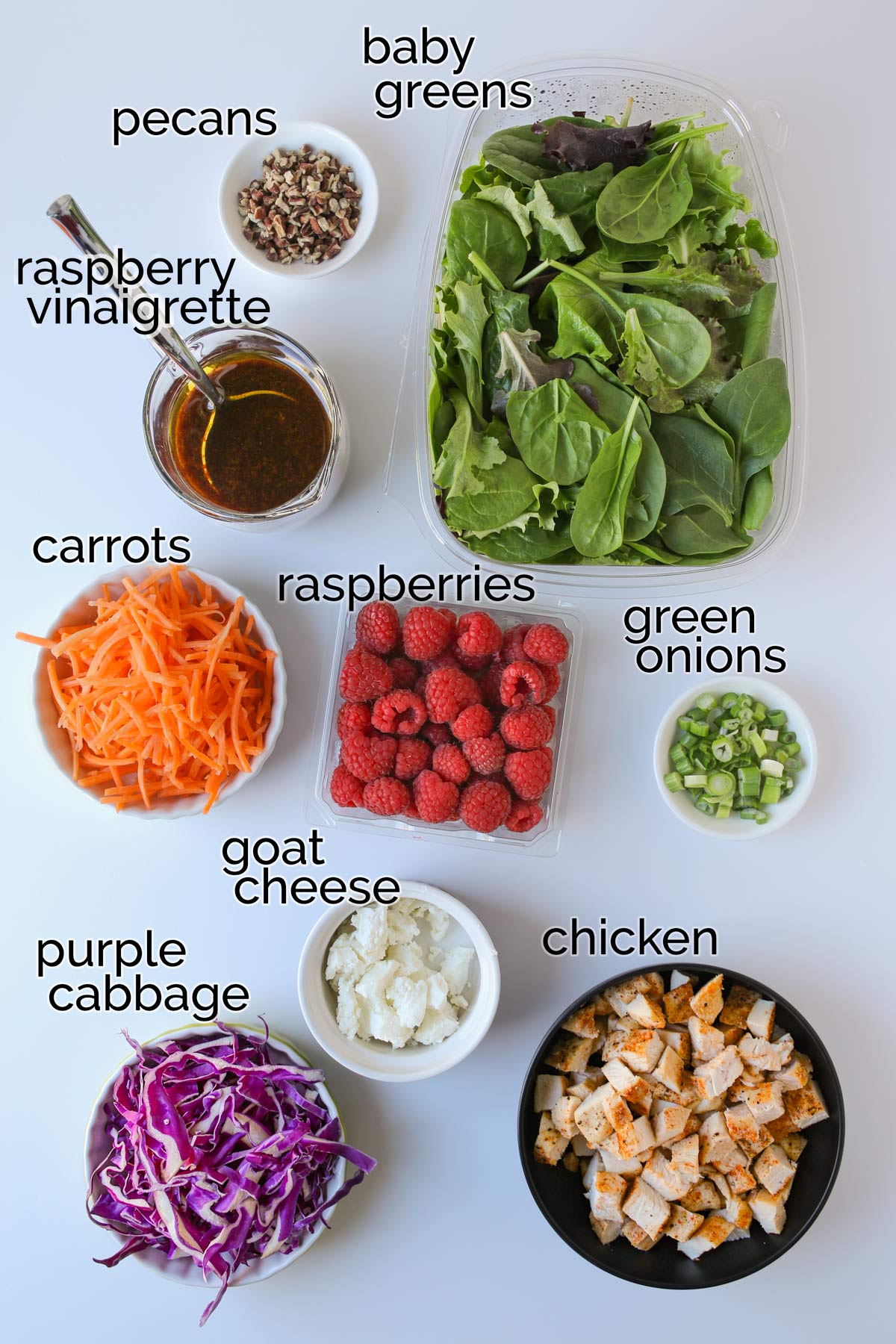 ingredients for chicken and raspberry salad laid out on white table.