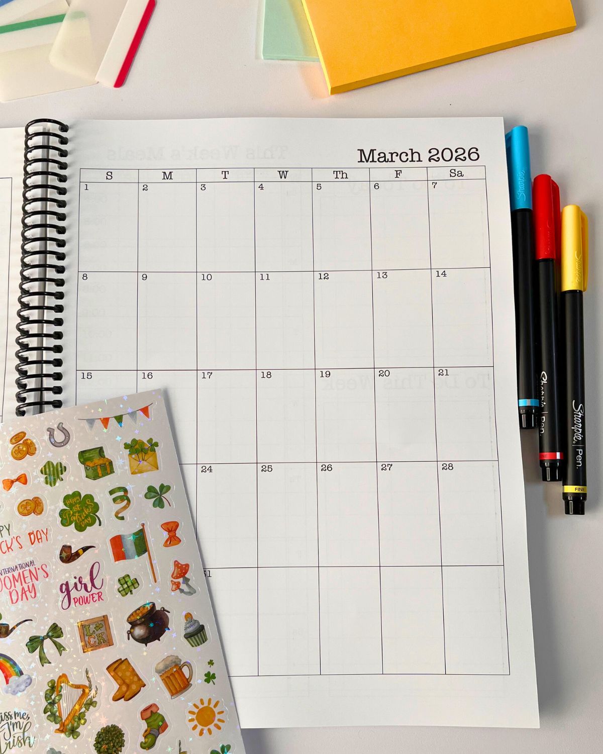 planner open to march 2026 page, with pens and stickers nearby.