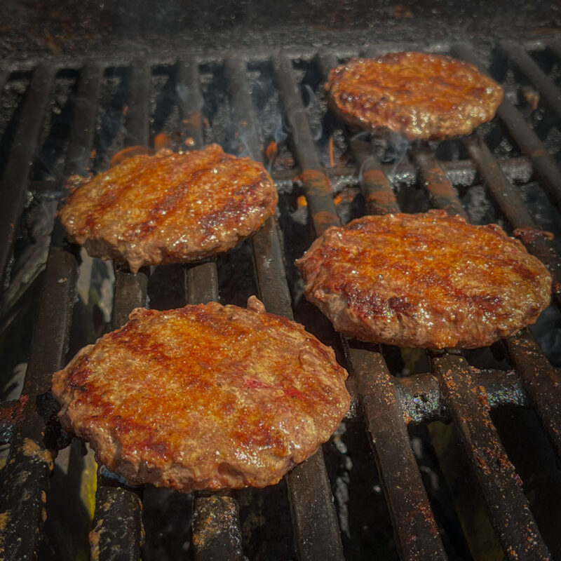 burgers cooked on grill with grill marks.