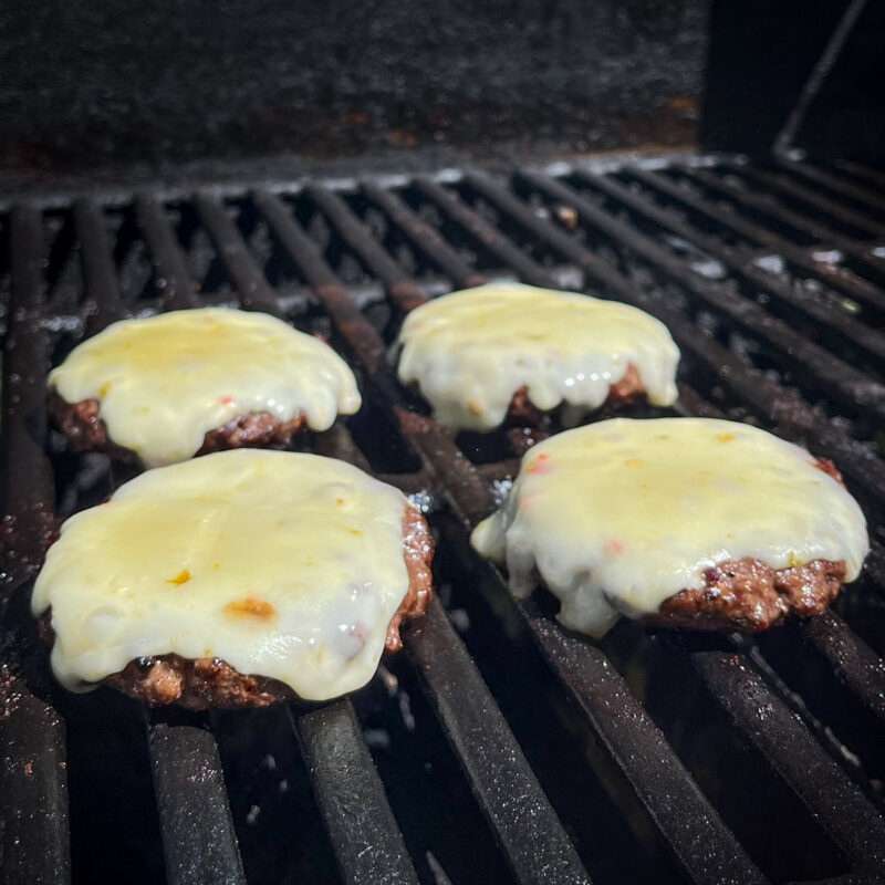 cheese melting on burgers on the grill.