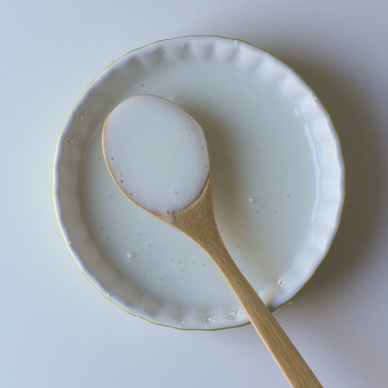 a wooden spoon scooping up some of the glaze in the small dish.