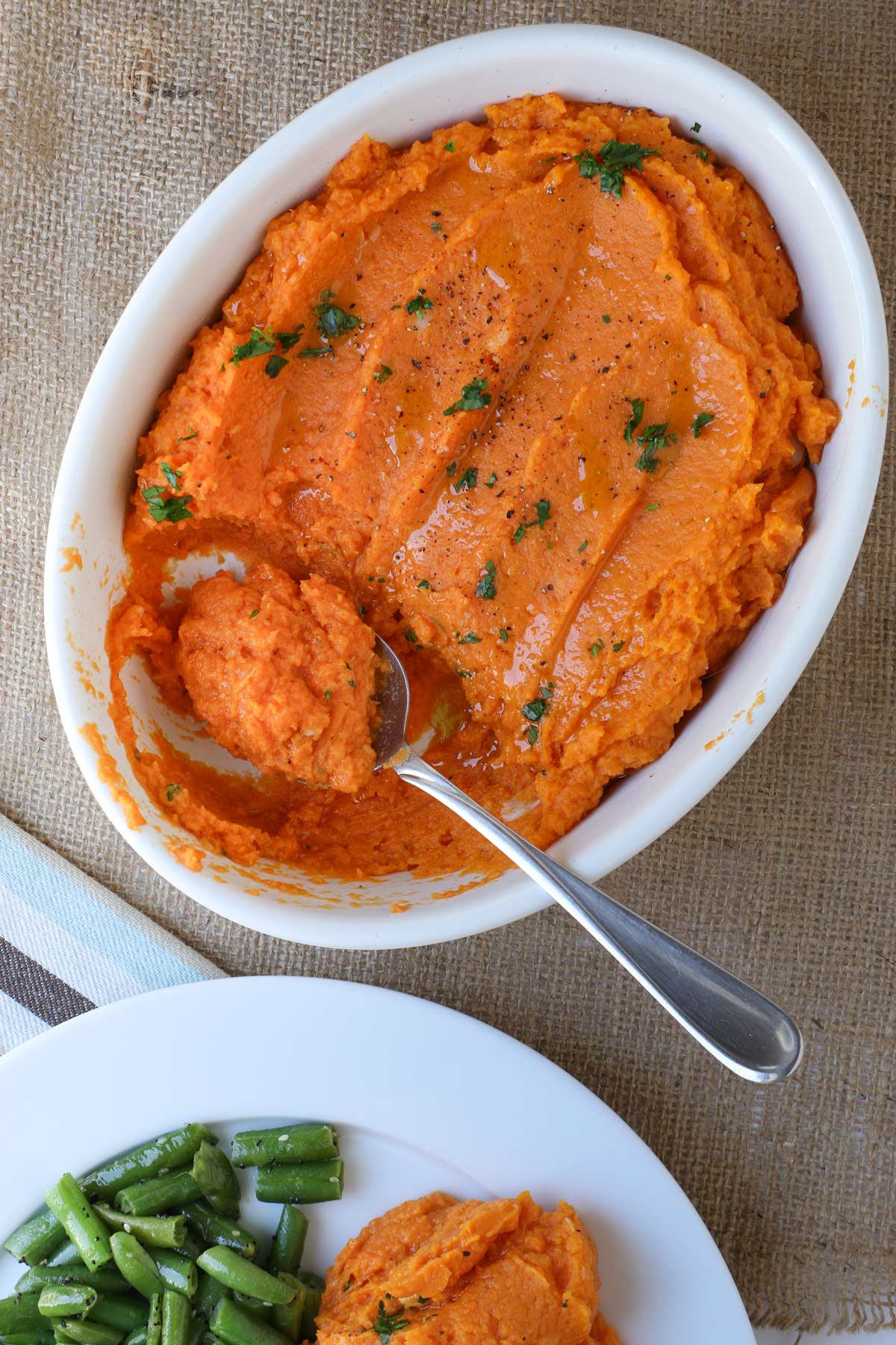 dish of mashed sweet potatoes with a spoon resting in a hollow where some has been scooped out.