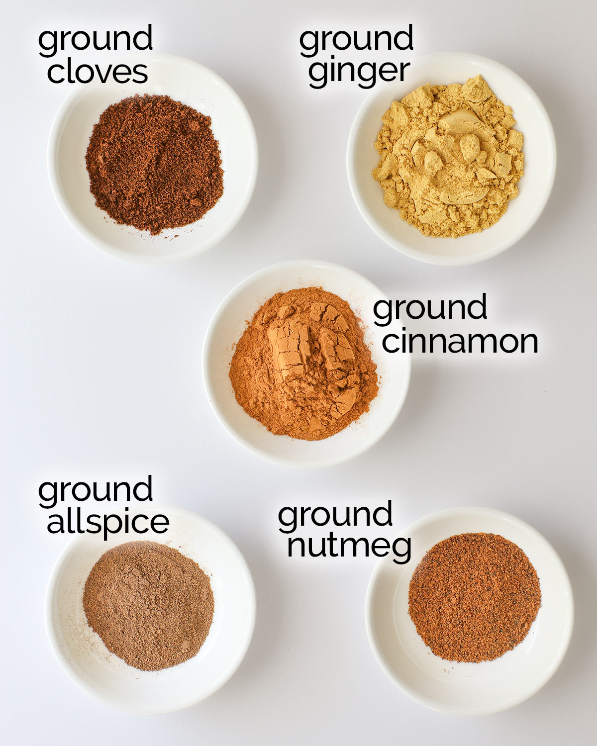 the different spices in pumpkin spice in small white dishes on a white table.