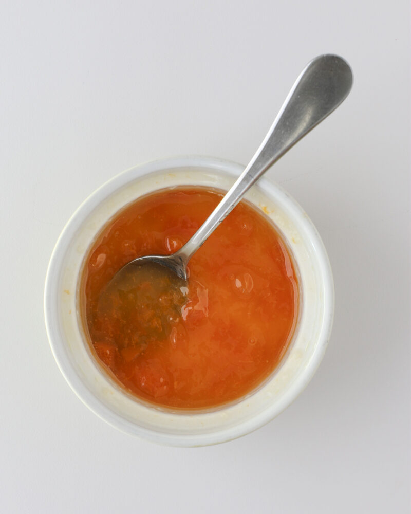 apricot glaze in a small bowl with a spoon.