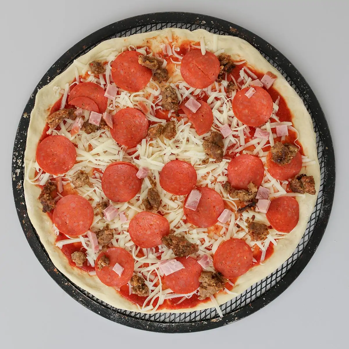 pizza round topped with sauce, cheese, and meats.