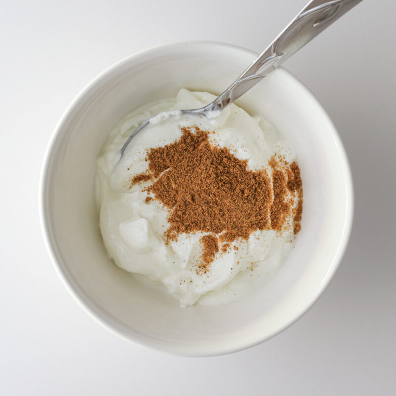 Greek yogurt and pumpkin spice in small bowl with a spoon.