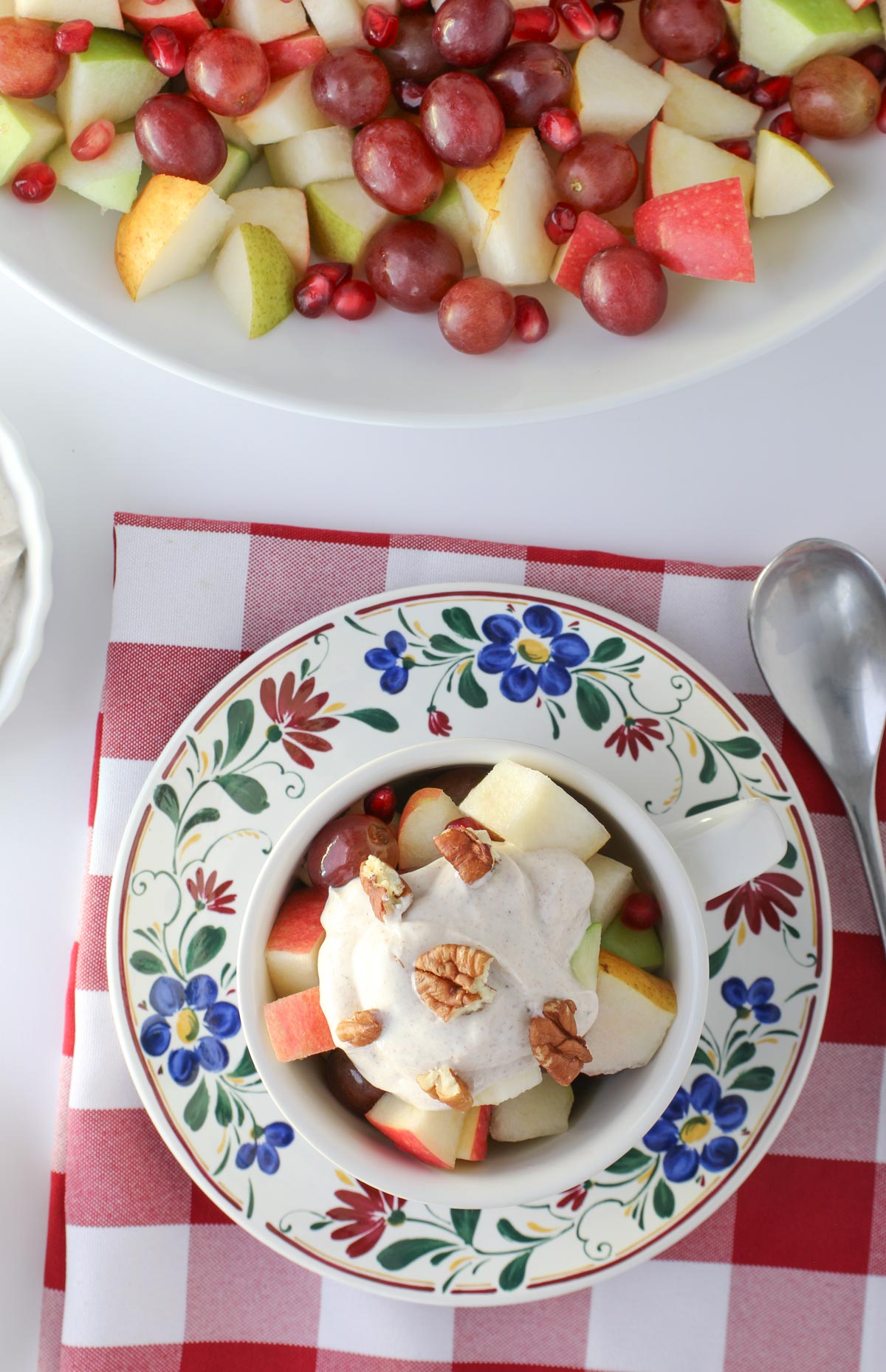 Thanksgiving fruit salad in a tea cup, topped with yogurt dip and chopped nuts.