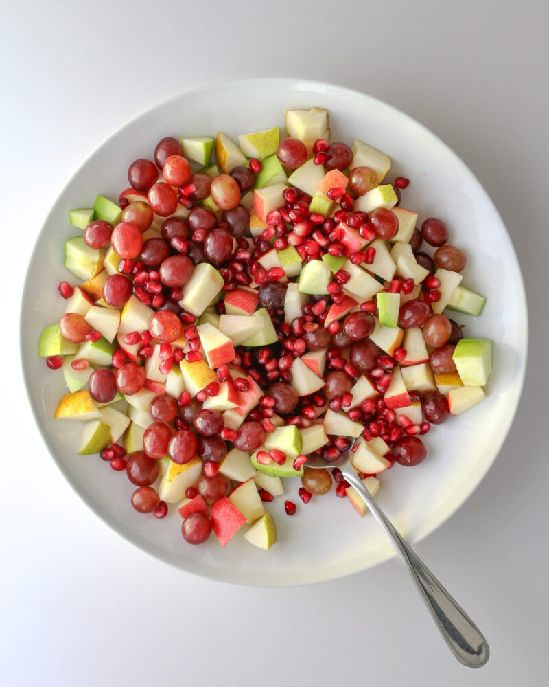 the combined fruits in the salad bowl with a serving spoon.