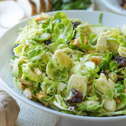 close up of brussels sprouts salad in a white bowl on dinner table.