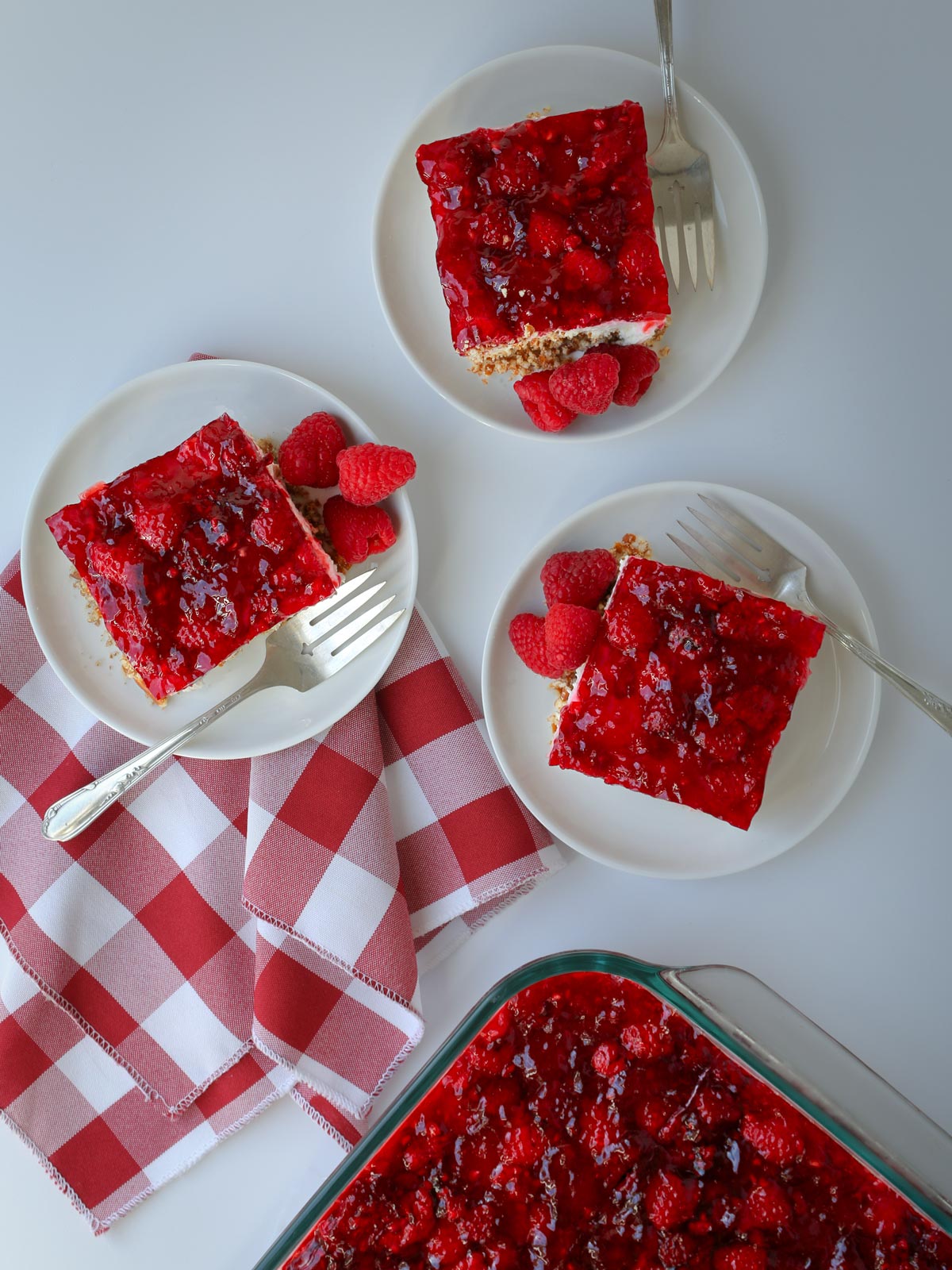 array of jello dessert squares on plates with red checked napkin.