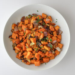 overhead shot of sweet potato salad in a white bowl on a white table.