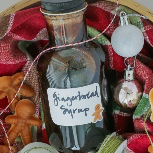 bottle of gingerbread syrup in a basket with twine and ornaments.