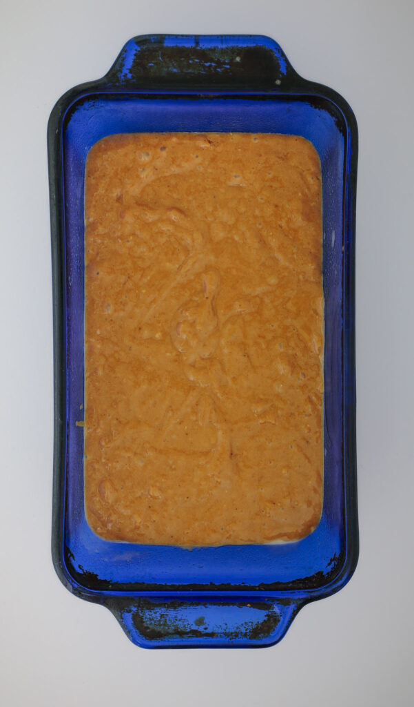 gingerbread batter in a blue glass loaf pan.