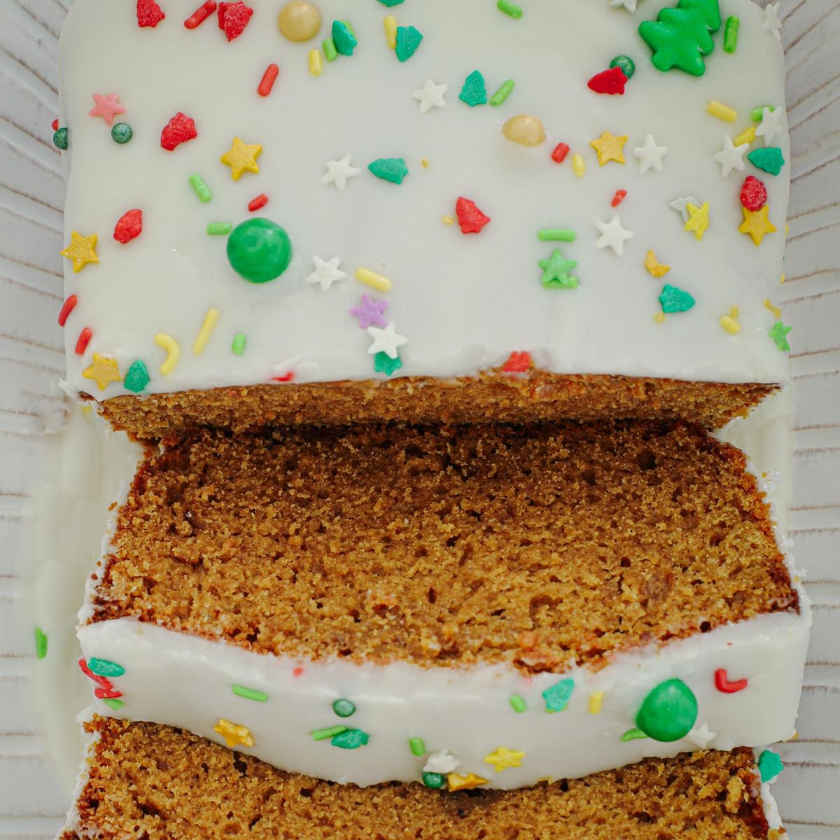 close up of gingerbread loaf cake sliced on a white platter.