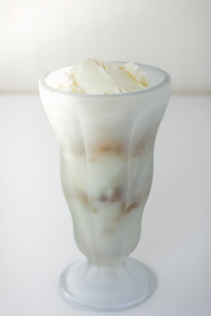 scoops of vanilla ice cream layered with cookie crumbs in a sundae glass.