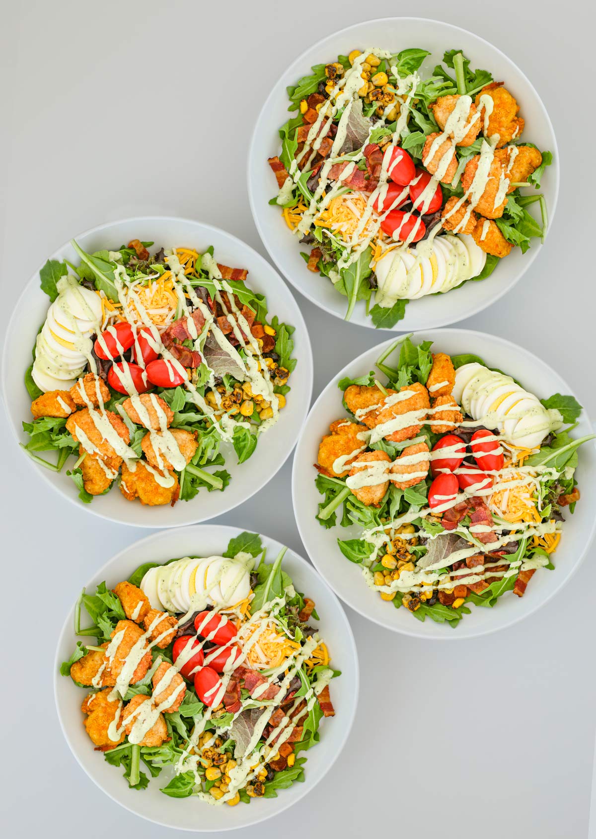 four salads topped with dressing.