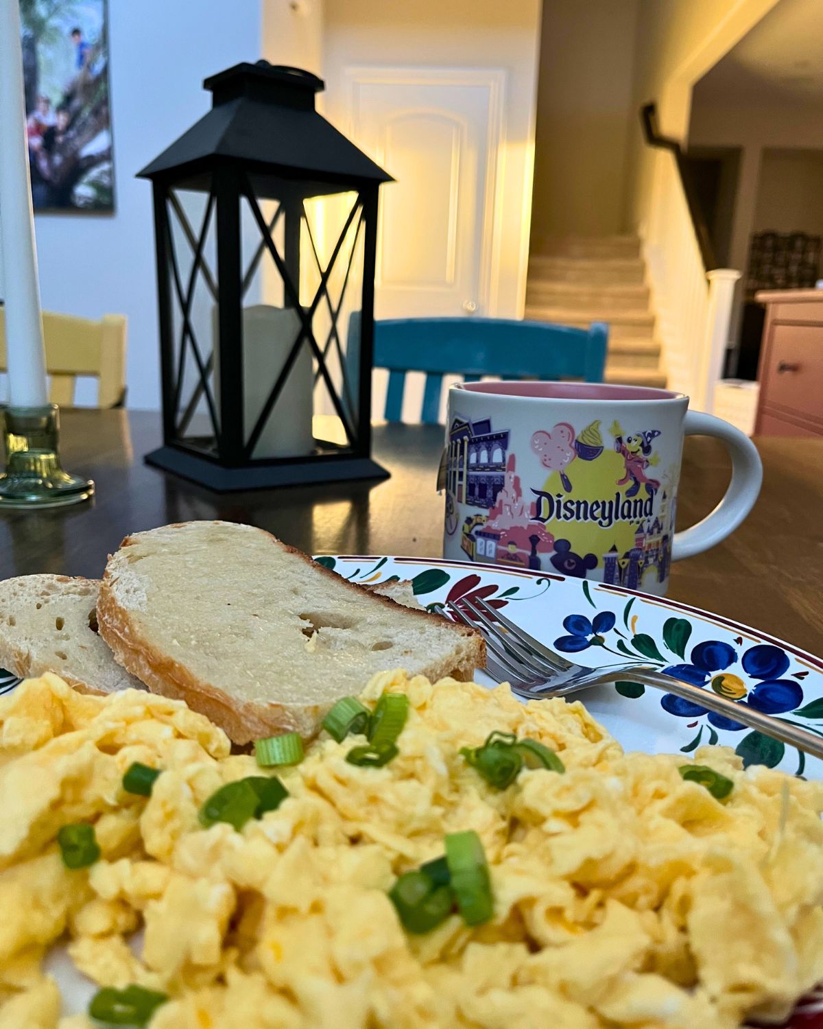 plate of scrambled eggs with green onions by a disneyland coffee mug.