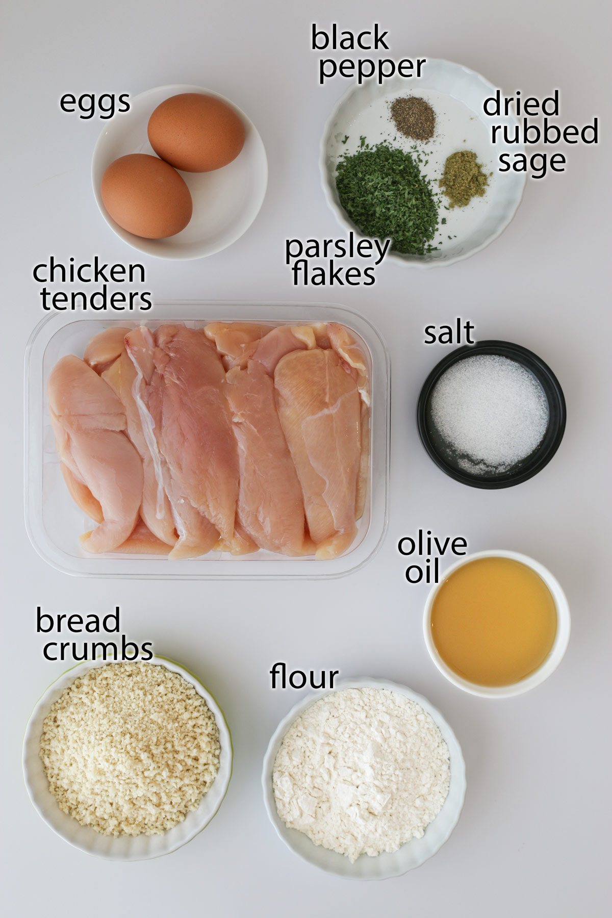 ingredients for fried chicken strips laid out on a white counter.