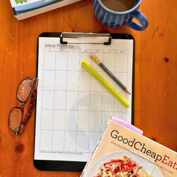 monthly menu plan worksheet on clipboard on table.