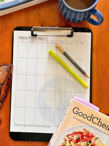 monthly menu plan worksheet on clipboard on table.