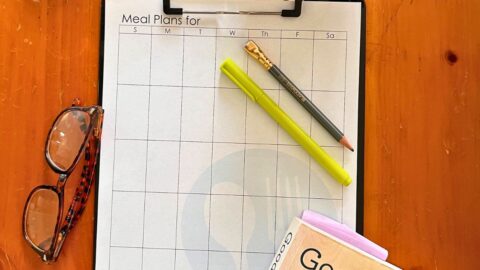 monthly menu plan worksheet on clipboard on table.