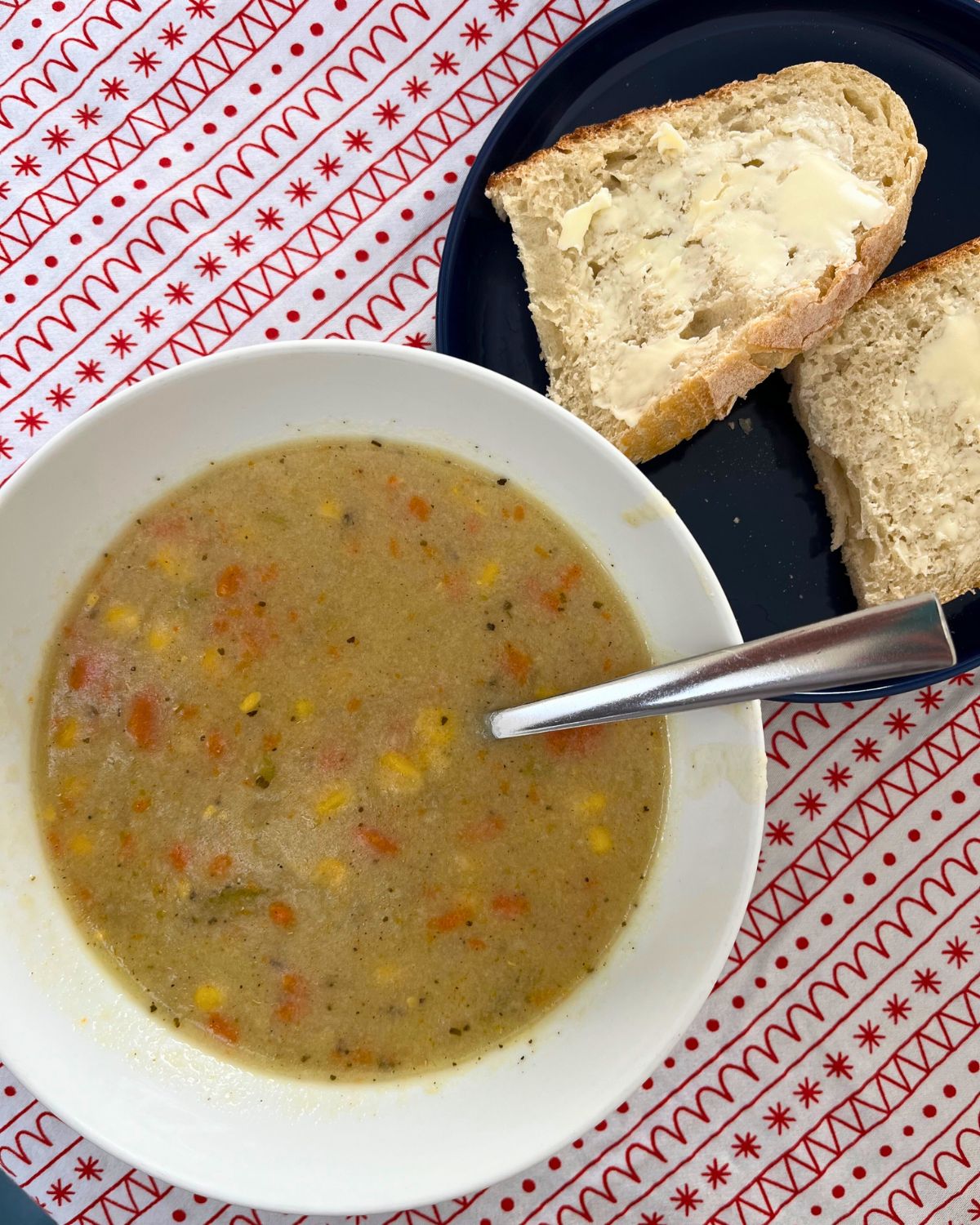 bowl of chowder next to blue plate of bread and butter.