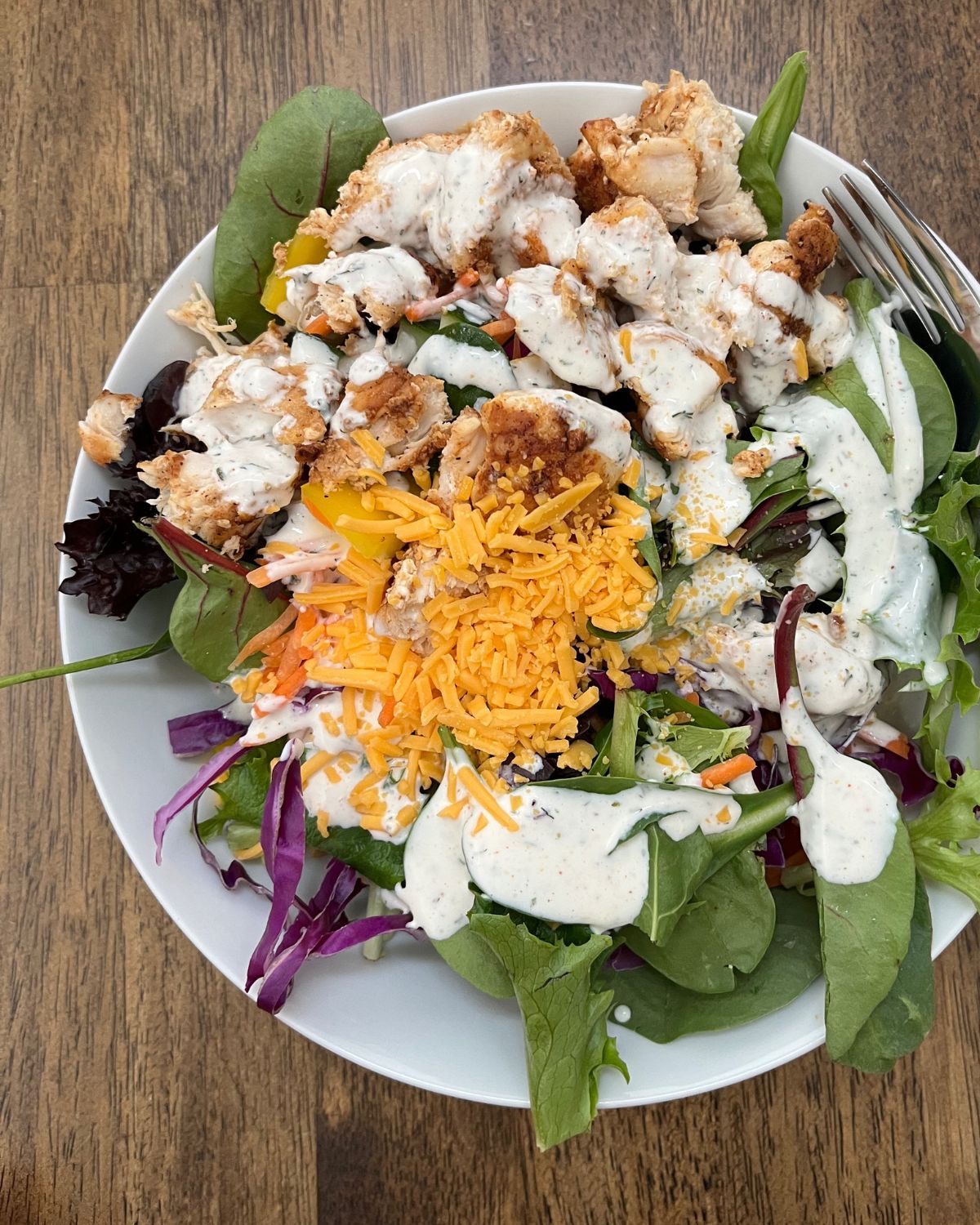 large green salad with chicken, cheddar, and ranch dressing.