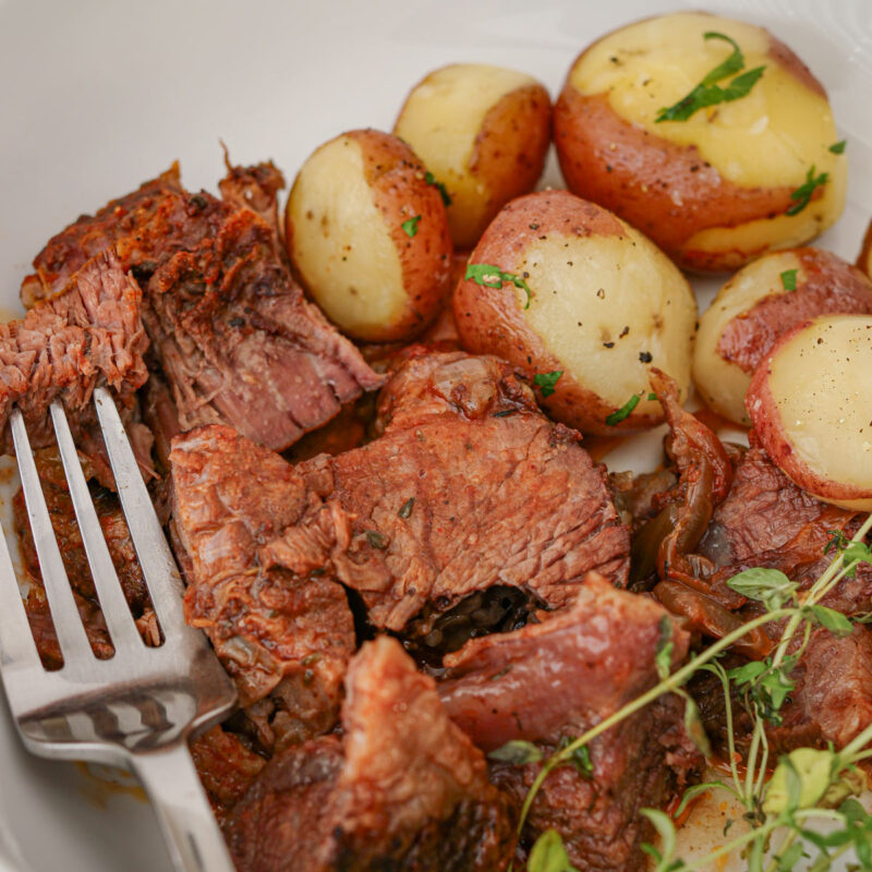 platter of roast with new potatoes and a fork.