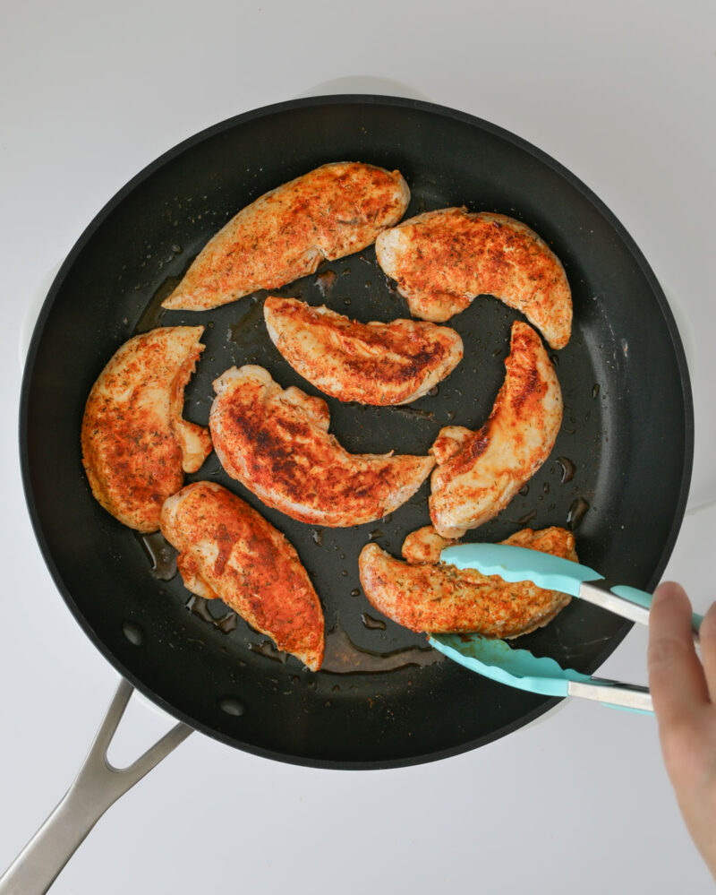 flipping the cooked chicken in the skillet.