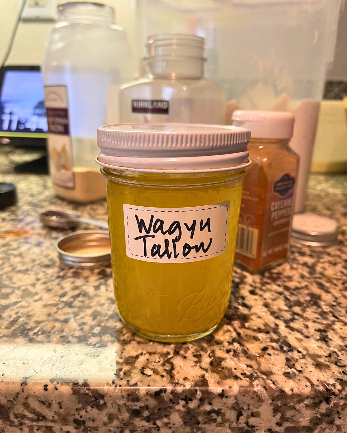 jar of wagyu tallow on counter with spices in background.