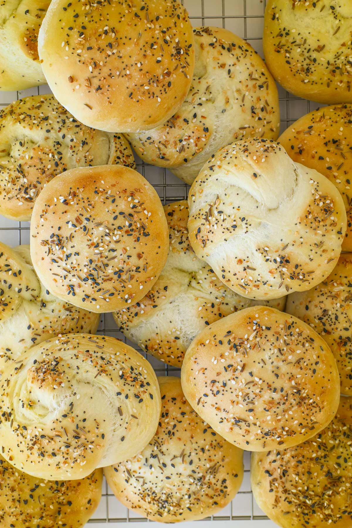 everything hamburger buns piled on a cooling rack.