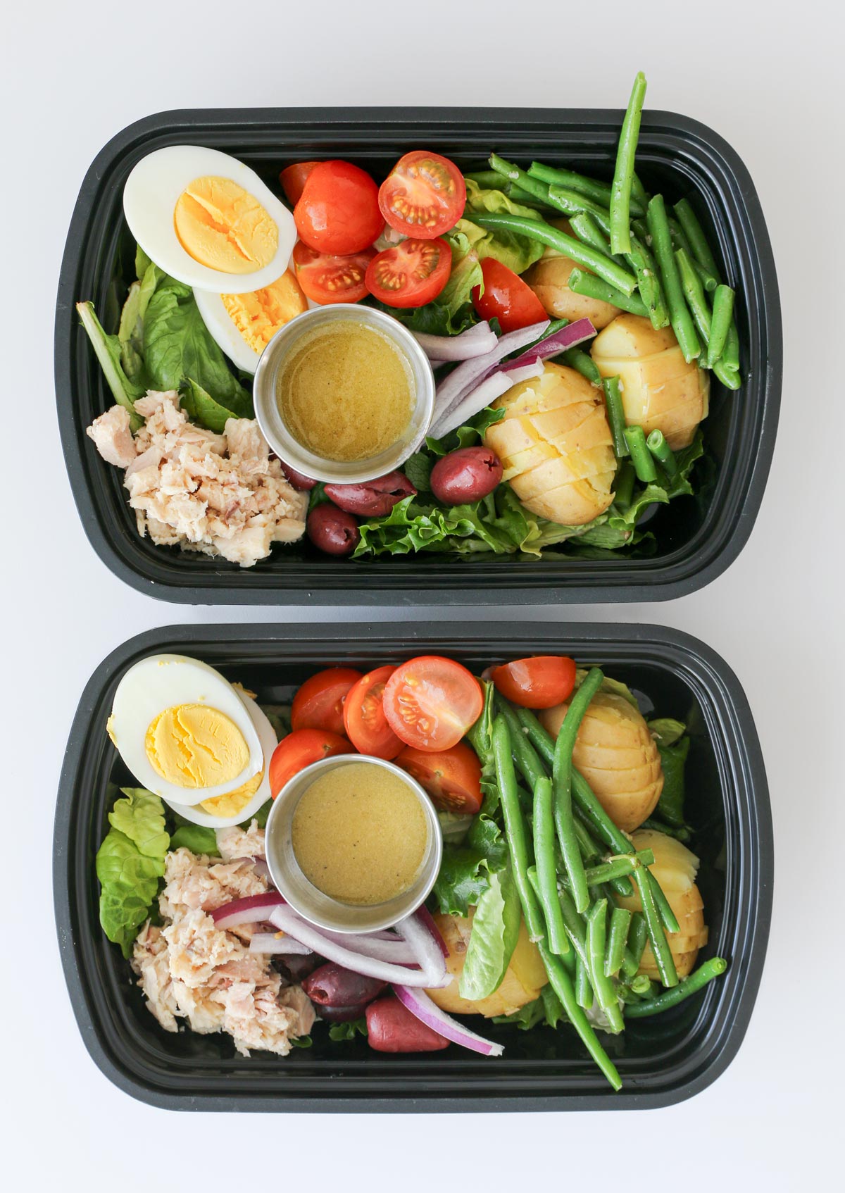 salad Nicoise made as a meal prep in black boxes.